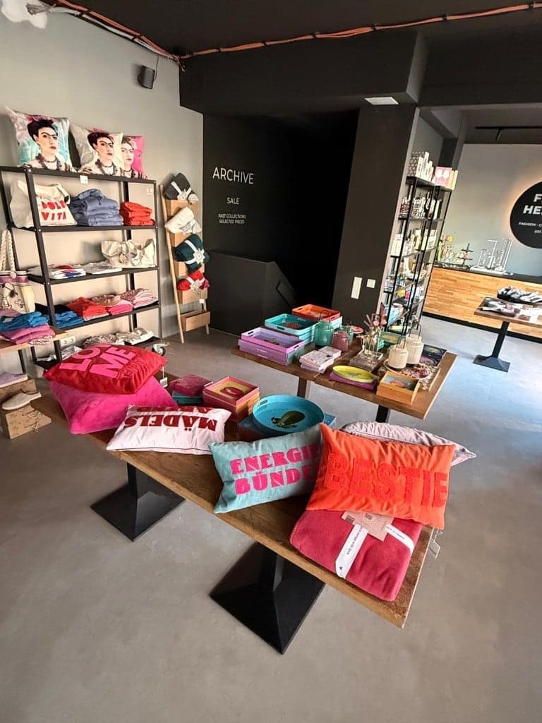 Tische mit bunten Kissen, Tabletts und Geschenkideen in Pink, Orange und Türkis